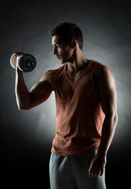sport, bodybuilding, training en mensen concept - jonge man met halter buigen spieren over grijze achtergrond