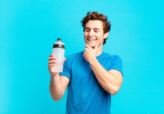 Sport boy smiling with a happy, confident expression with hand on chin, wondering and looking to the side. energy drink concept