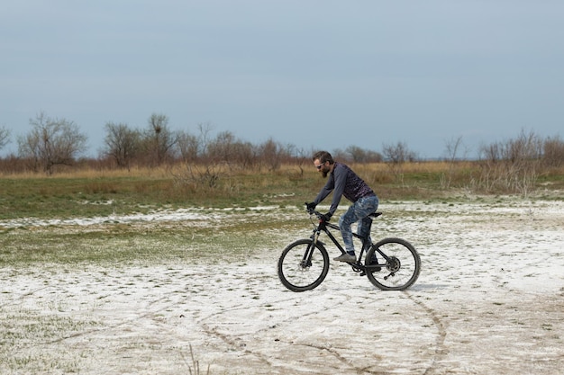 Sport brute bebaarde man op een moderne mountainbike Een fietser op een zout verlaten plek aan het meer