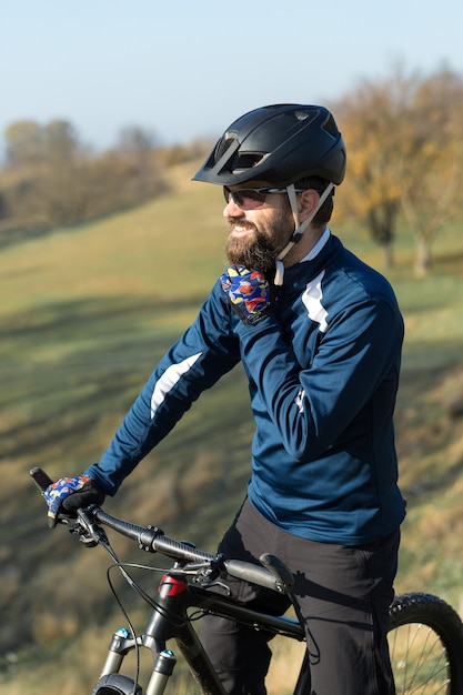 Sport brute bebaarde man op een moderne mountainbike. Een fietser op een zout verlaten plek aan het meer.