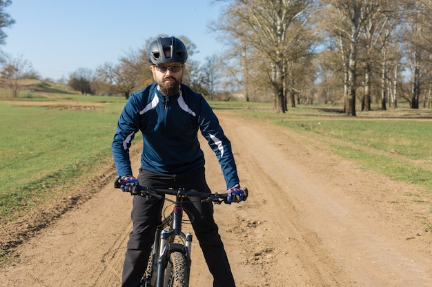 Sport brute bebaarde man op een moderne mountainbike. Een fietser op een zout verlaten plek aan het meer.