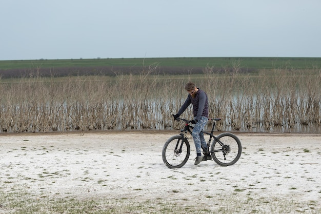 Sport brute bebaarde man op een moderne mountainbike Een fietser op een zout verlaten plek aan het meer