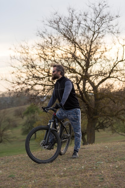 Sport brute bebaarde man op een moderne mountainbike Fietser op de groene heuvels in de lente