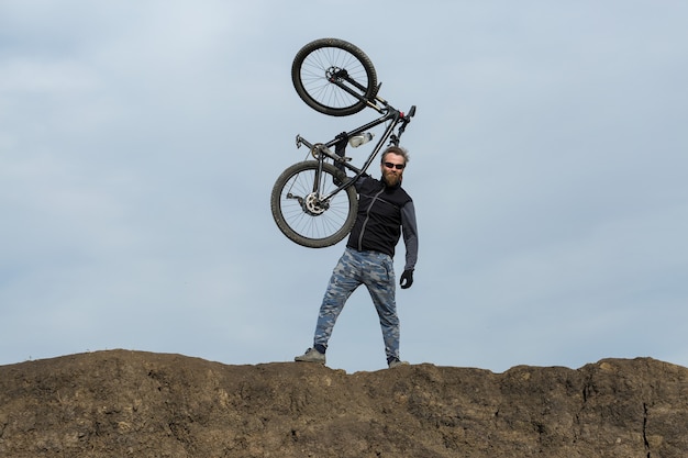 Sport brute bebaarde man op een moderne mountainbike Prachtig uitzicht vanaf de berg