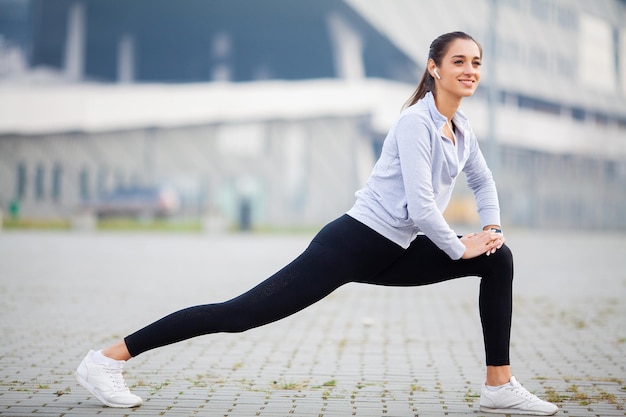 Sport buiten vrouw luistert naar muziek op de telefoon terwijl ze buiten aan het sporten is