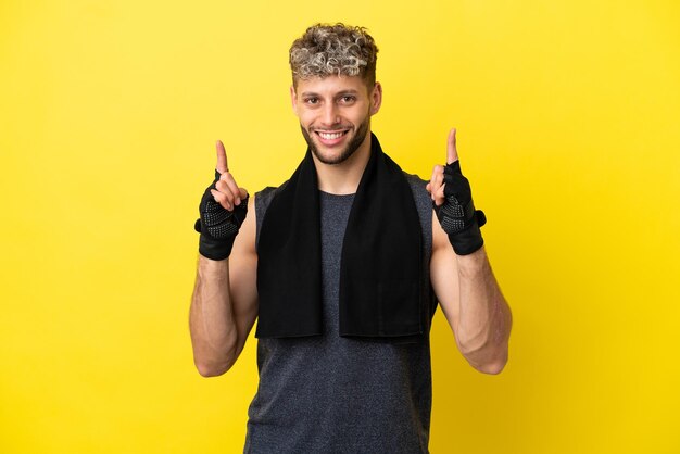 Sport caucasian man isolated on yellow background pointing up a great idea