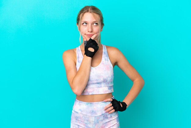 Sport caucasian woman isolated on blue background having doubts and with confuse face expression