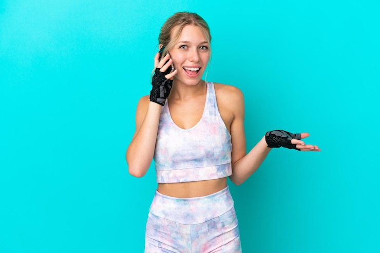Photo sport caucasian woman isolated on blue background keeping a conversation with the mobile phone with someone