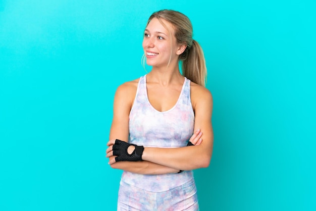 Sport caucasian woman isolated on blue background looking side