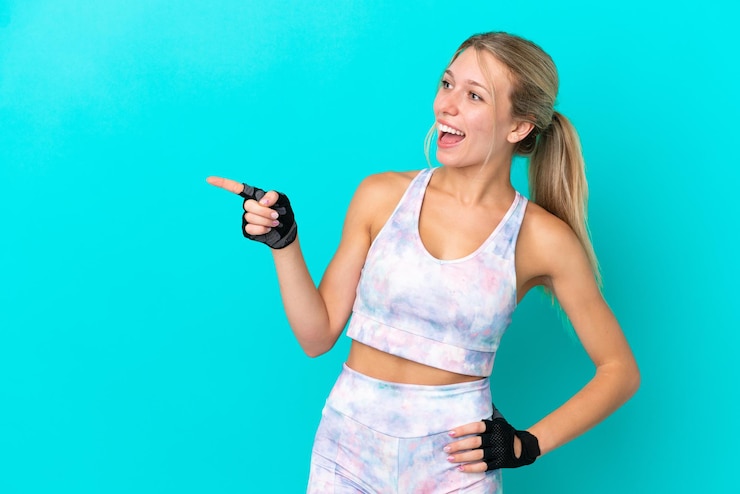 Photo sport caucasian woman isolated on blue background pointing finger to the side and presenting a product