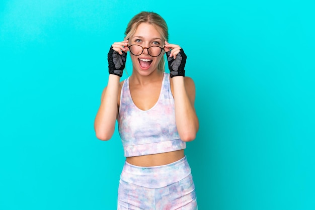 Sport caucasian woman isolated on blue background with glasses and surprised