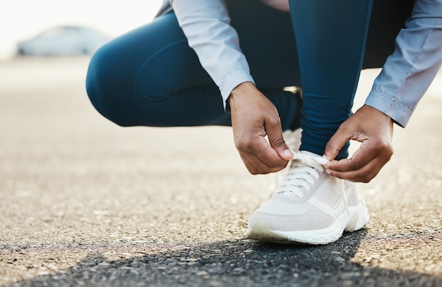 Sport close-up en vrouw stropdas schoenen buiten op de weg voor hardlooptraining in de stad Fitness gezondheid en zoom van vrouwelijke atleet die haar veters koppelt voor cardio-oefening voor race- of marathontraining