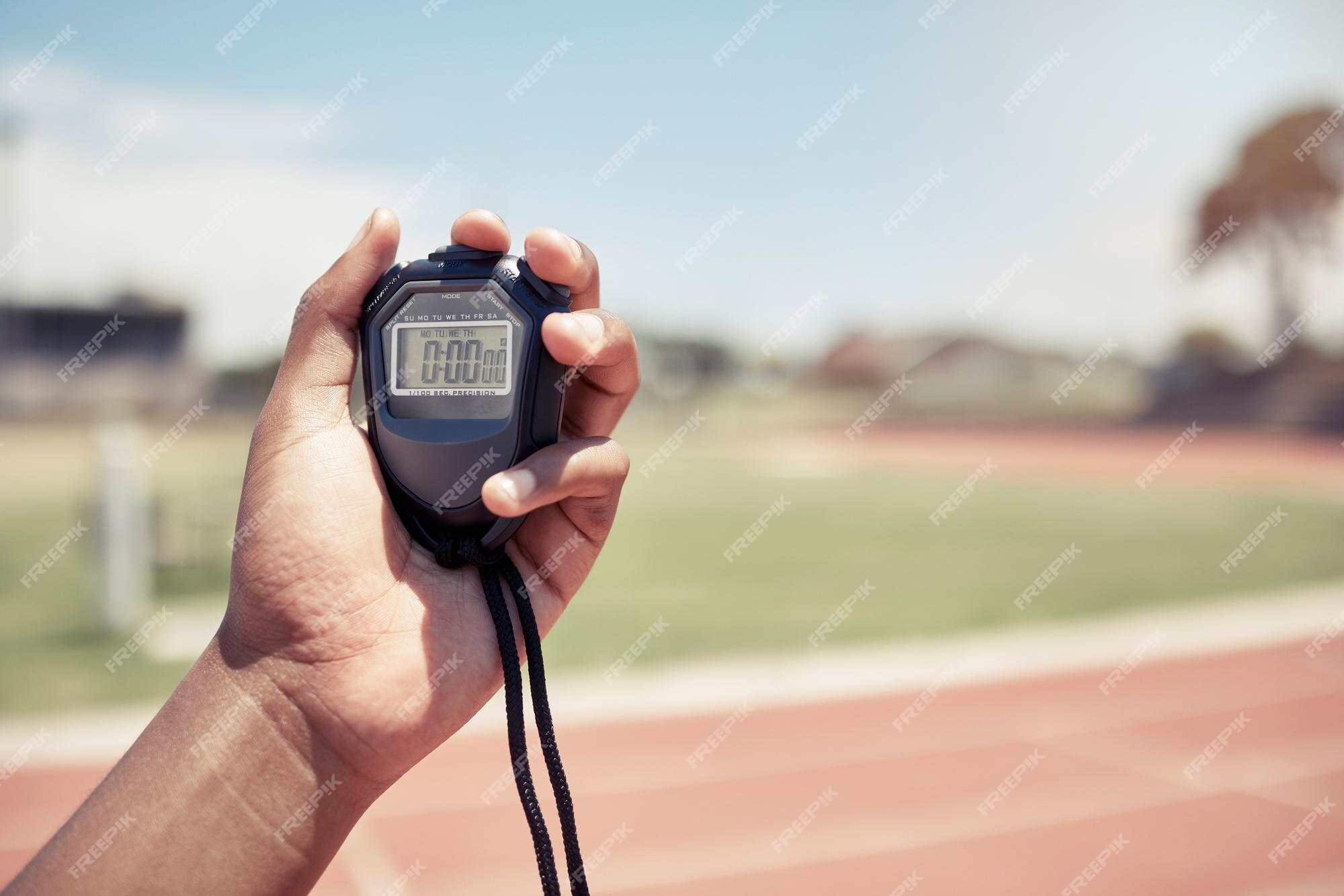 Measuring The Running Speed Of An Athlete Using A Mechanical Stopwatch.  Hand With A Stopwatch On The Background Of The Legs Of A Runner. Stock  Photo, Picture and Royalty Free Image. Image