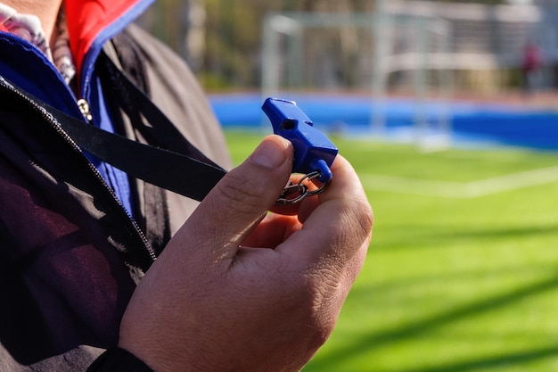 A sport coach with a whistle ready to command the team outdoors on the football green field