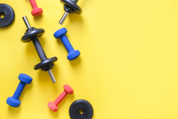 Sport colorful dumbbells on yellow.