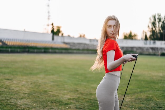 Sport concept jonge vrouw met springtouw in haar handen meisje tegen de achtergrond van groen gras