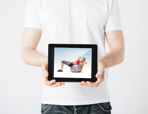 sport concept - man holding tablet pc with picture of woman doing exercise