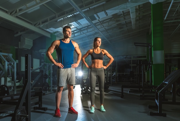 La coppia sportiva sta in palestra sullo sfondo luminoso