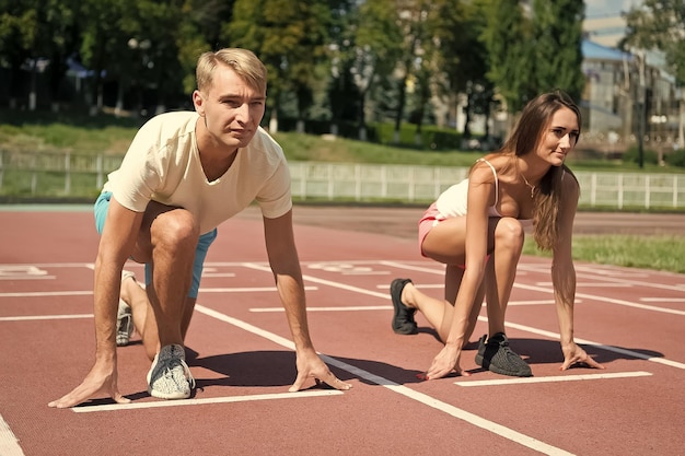 Спортивная пара начинает соревнования бег на арене трек солнечное лето на открытом воздухе