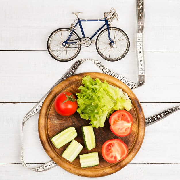 Sport and diet concept bicycle model fresh vegetables and centimeter tape