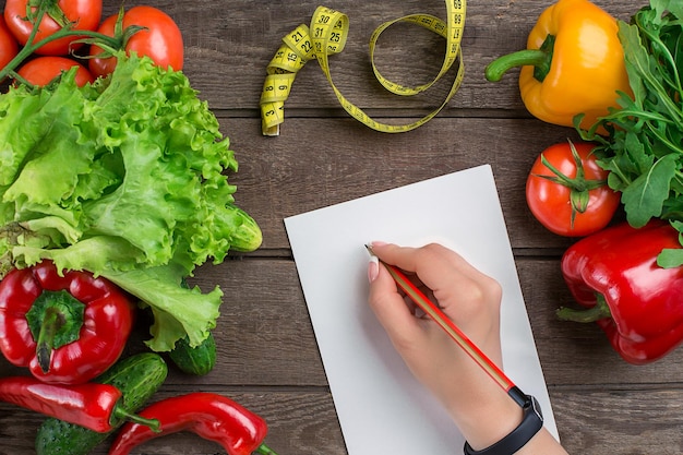 Sport e dieta. verdure e centimetro. peperoni, pomodori, insalata su fondo rustico