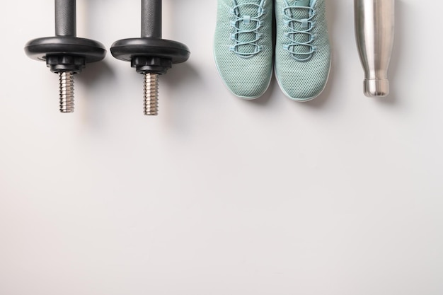 Sport- en fitnessapparatuur halters schoenen waterfles op grijs Bovenaanzicht ruimte voor uw tekst