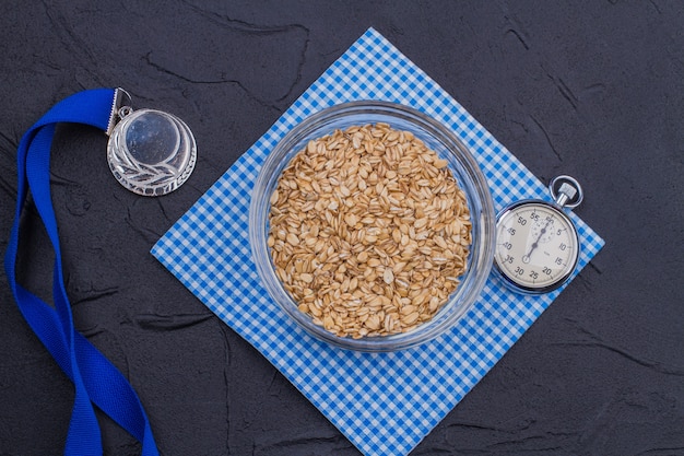 Sport en gezonde levensstijl concept plat lag. Plaat van havermout met zilveren medaille en stopwatch.