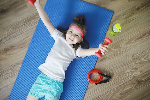 Sport en gezonde levensstijl. Kind sporten thuis. Yogamat halter en springtouw. Sportachtergrond met het concept van huisoefeningen.