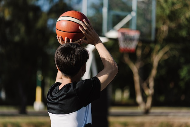 Sport- en recreatieconcept een jonge mannelijke tiener die na school een basketbal apart in de rechtbank oefent