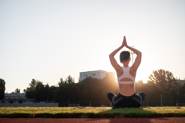 Sport en welzijn. Fitness meisje in witte sneakers stretching training doen. Mode sportieve vrouw met sterke gespierde lichaamstraining. Fit vrouw die zich uitstrekt in openluchtstadion