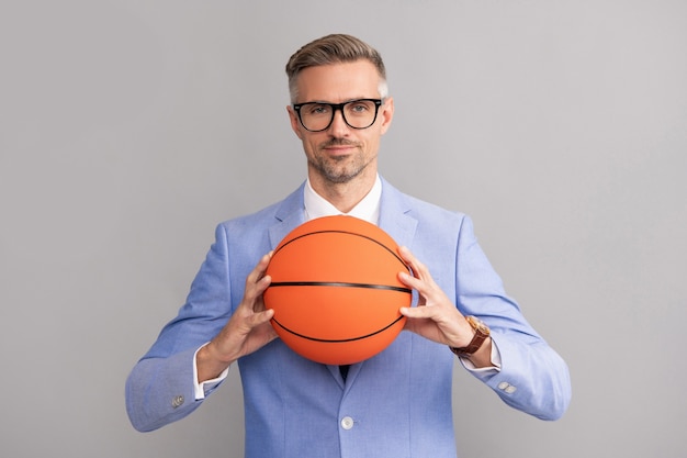 Sport en zakelijk succes. activiteit voor zelfverzekerde baas. volwassen zakenman in formalwear en bril. succesvolle man met basketbalbal.