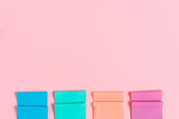 Sport equipment, resistance bands on the pink background, copy space.