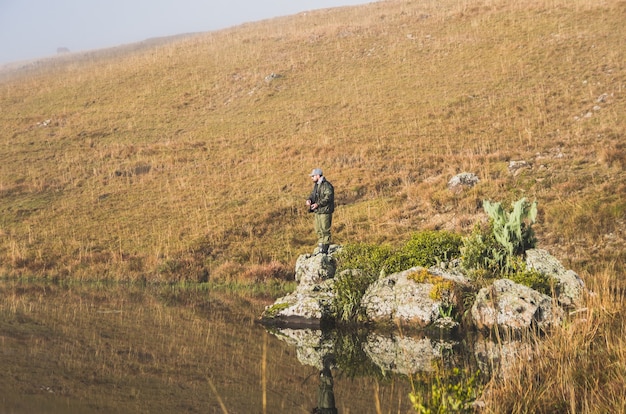 Sport fisherman fishing in lake on cloudy day.