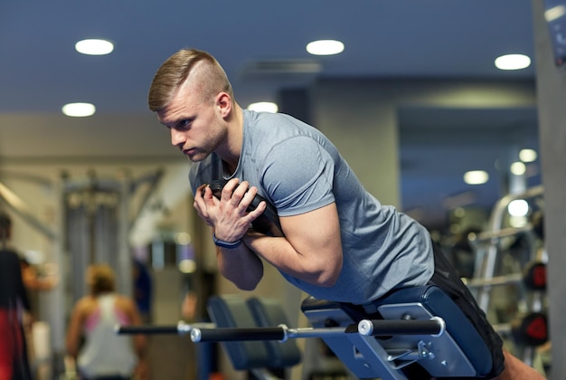 sport, fitness, bodybuilding, levensstijl en mensenconcept - jonge man die rug- en buikspieren buigt op de bank in de sportschool