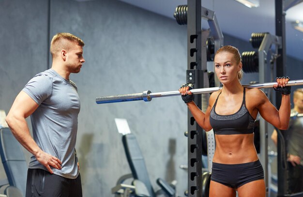 sport, fitness, bodybuilding, lifestyle and people concept - man and woman with barbell flexing muscles in gym
