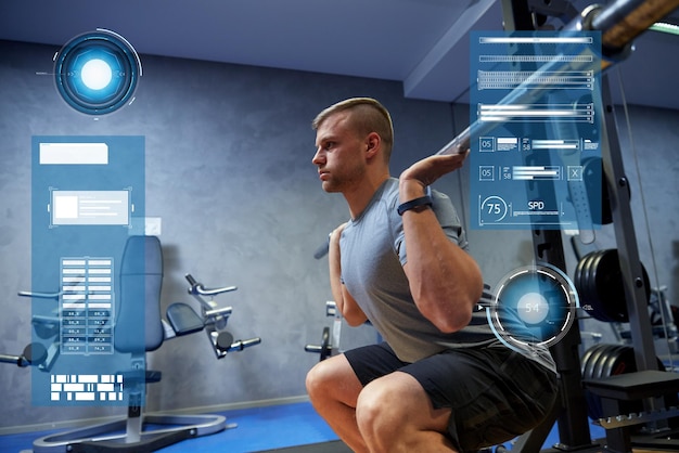 sport, fitness, bodybuilding and people concept - young man with barbell flexing muscles in gym over virtual charts