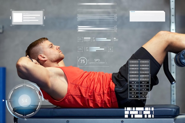 sport, fitness, bodybuilding, sporten en mensenconcept - jonge man die buikspieroefeningen maakt in de sportschool over virtuele grafieken