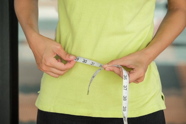 Photo sport fitness and diet concept - close up of trained belly with measuring tape