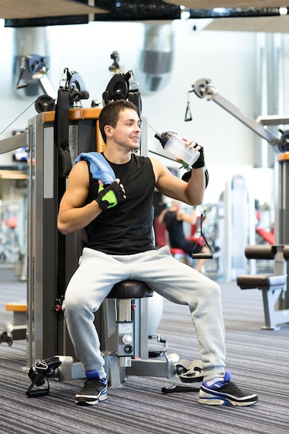 sport, fitness, equipment, lifestyle and people concept - smiling man exercising on gym machine