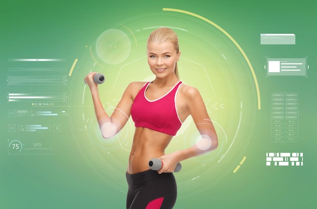 Photo sport, fitness, exercising, technology and people concept - happy young sporty woman with dumbbells flexing biceps over green background