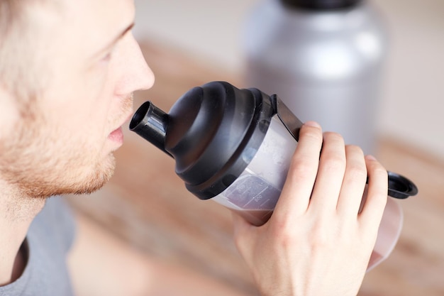 Sport, fitness, gezonde levensstijl en mensenconcept - close-up van de mens met pot en fles die eiwitshake drinkt