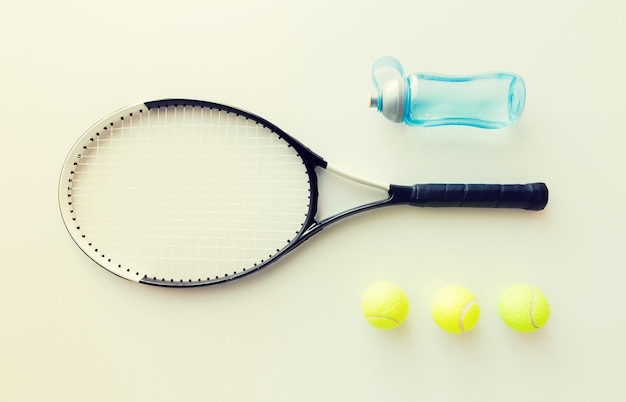 sport, fitness, healthy lifestyle and objects concept - close up of tennis racket with balls and bottle