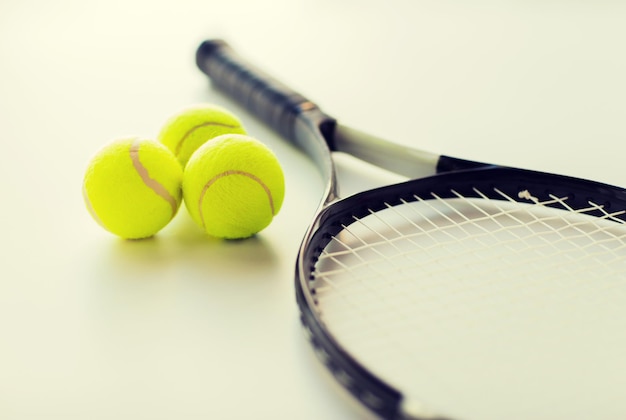sport, fitness, healthy lifestyle and objects concept - close up of tennis racket with balls