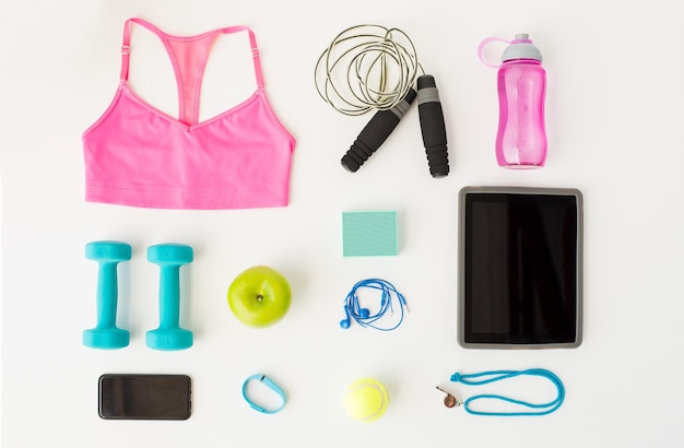 sport, fitness, healthy lifestyle, technology and objects concept - close up of tablet pc computer with smartphone and sports stuff over white background