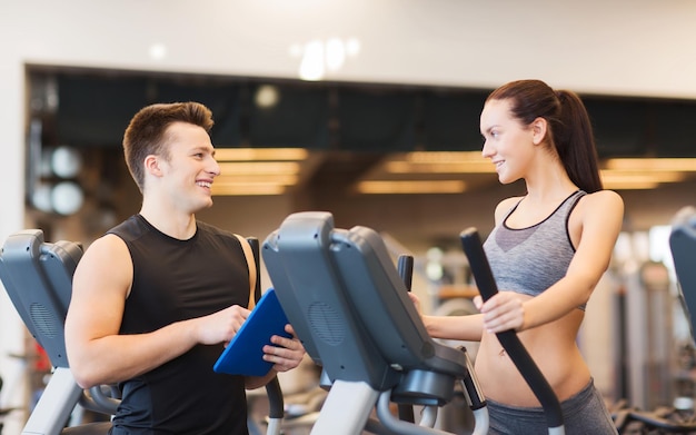 sport, fitness, levensstijl, technologie en mensenconcept - vrouw met trainer die op stepper in gymnastiek uitoefent