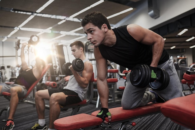 sport, fitness, lifestyle and people concept - group of men flexing muscles with dumbbells in gym