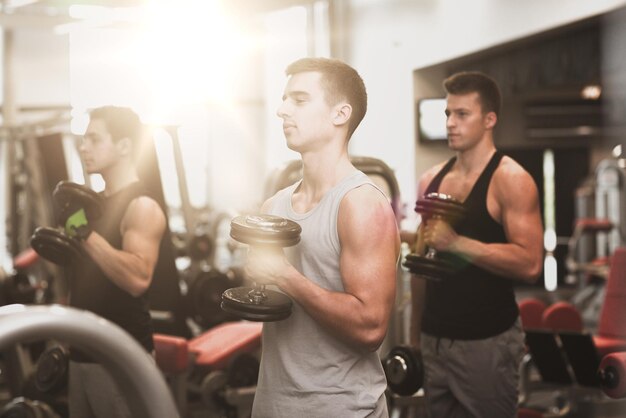 sport, fitness, lifestyle and people concept - group of men with dumbbells in gym