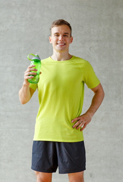 sport, fitness, lifestyle and people concept - smiling man with bottle of water in gym