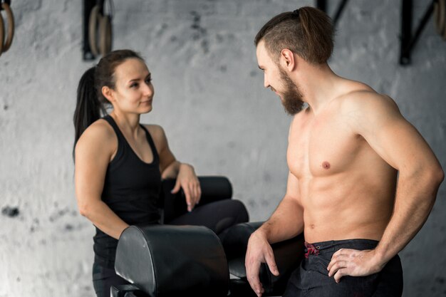 Sport, fitness, lifestyle and people concept - smiling man and woman in gym