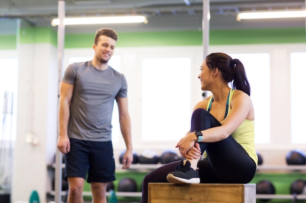 Photo sport, fitness, lifestyle and people concept - smiling man and woman with heart rate tracker in gym